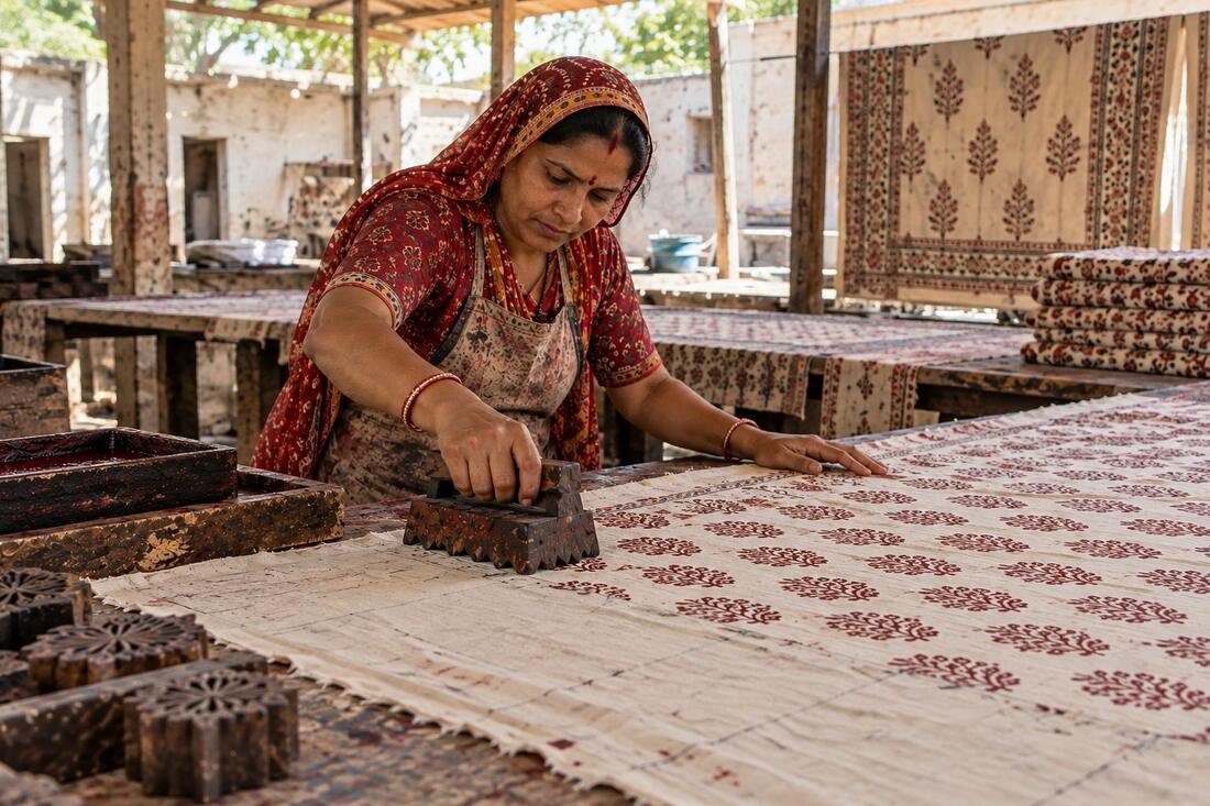 A woman artisan in Rajasthan pressing a carved wooden block onto cloth for hand block printing